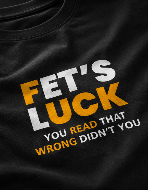 Close-up of a black t-shirt featuring a bold graphic print with the text 'FET'S LUCK YOU READ THAT WRONG DIDN'T YOU' in white and yellow lettering.